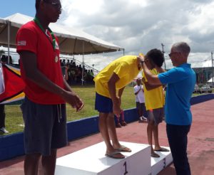 Guyana's Business Minister, Dominic Gaskin, presents Hannibal Gaskin with one of his four gold medals 