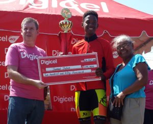 Digicel's CEO, Kevin Kelly, presents Jamal John with his prizes. Sharing the moment with the rider is his mother